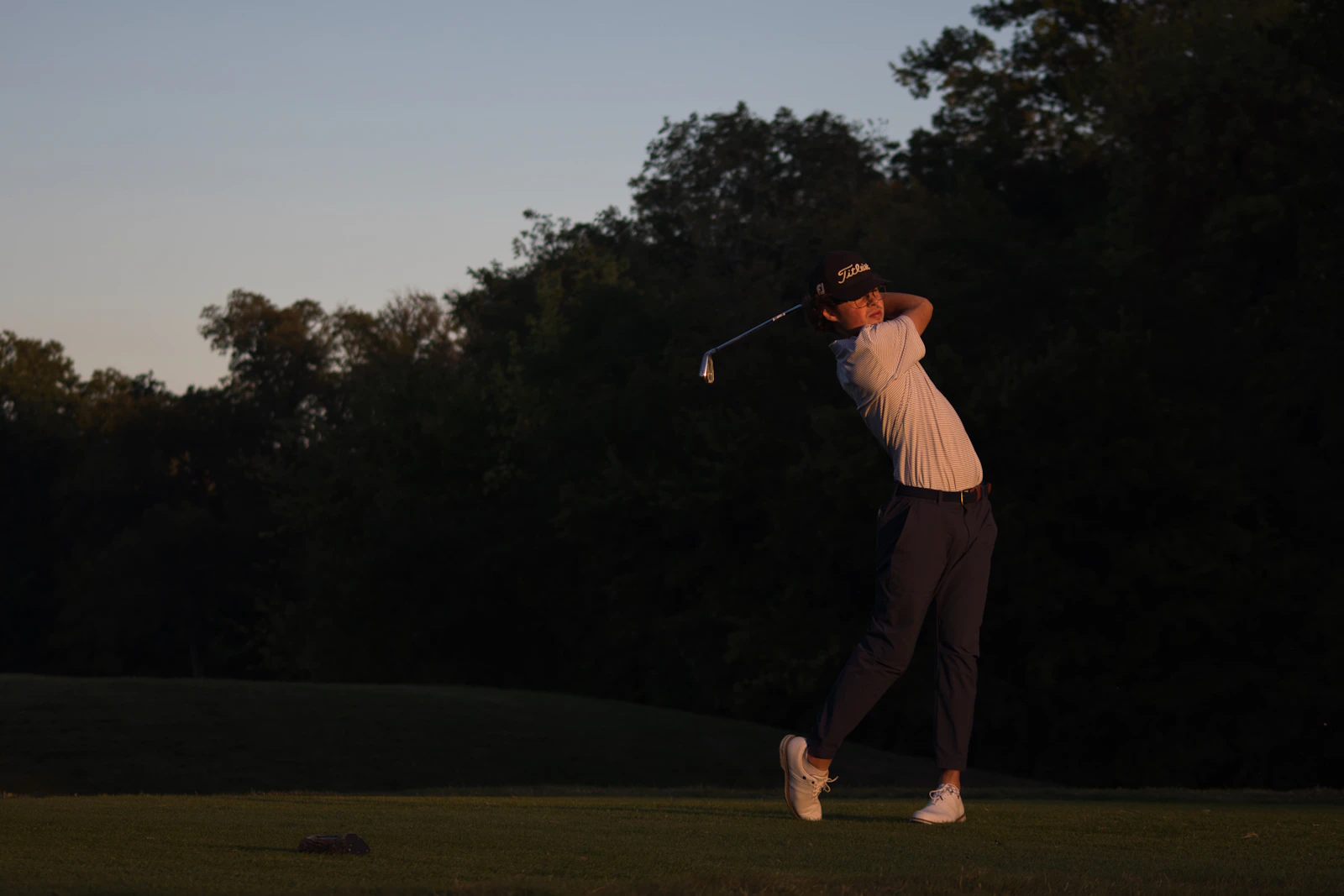 Golfista terminando su swing con la luz del atardecer